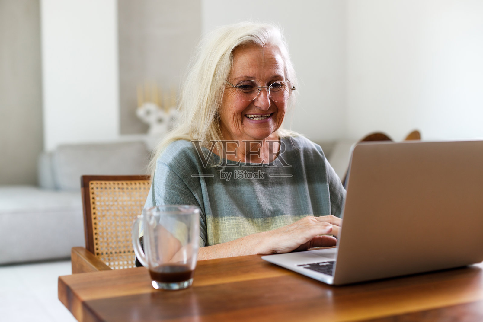 自信的老年女性在家中熬夜工作时使用笔记本电脑并微笑照片摄影图片