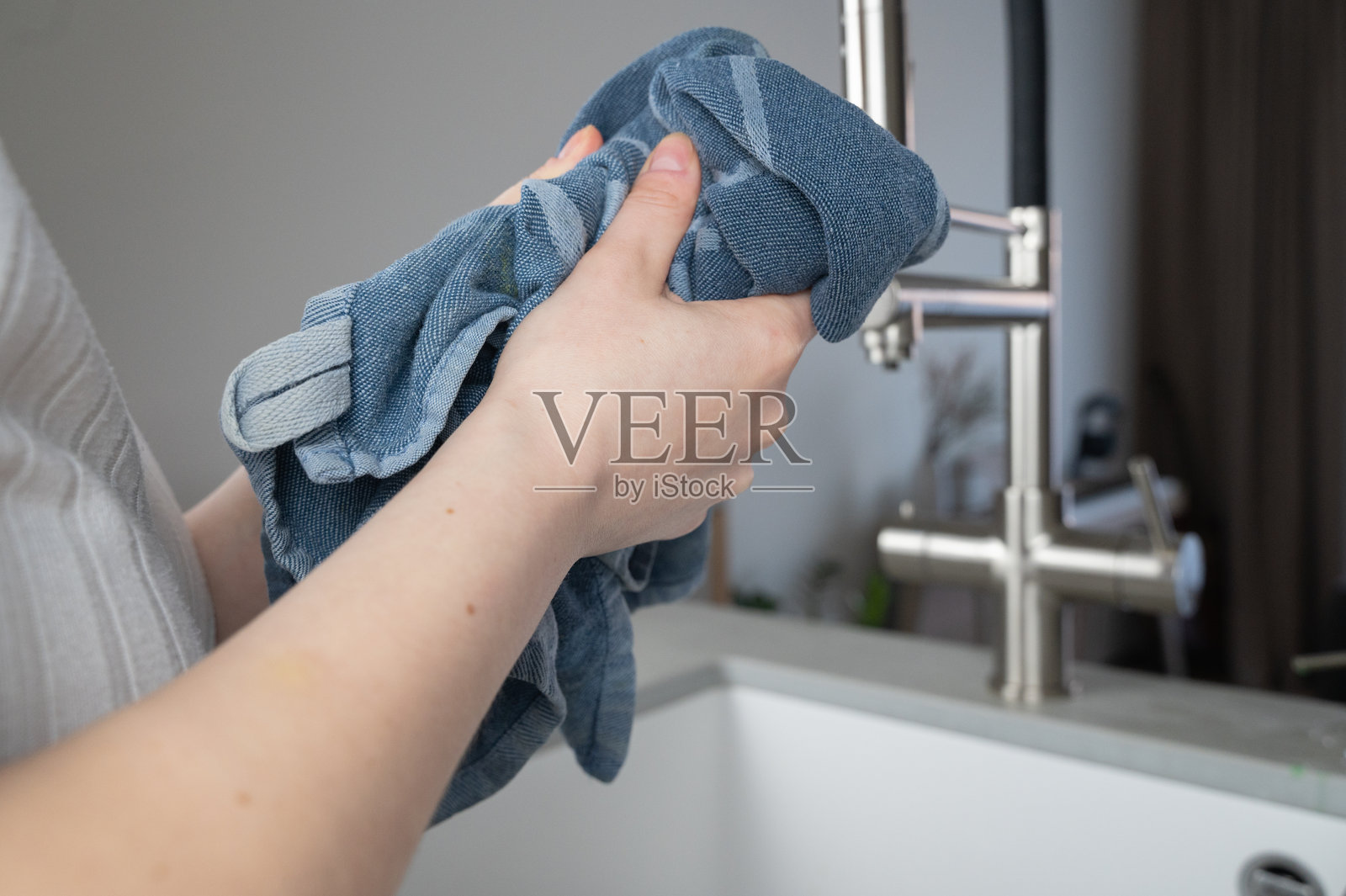 在厨房水槽小心地洗涤牛仔布，专注于整个过程。照片摄影图片