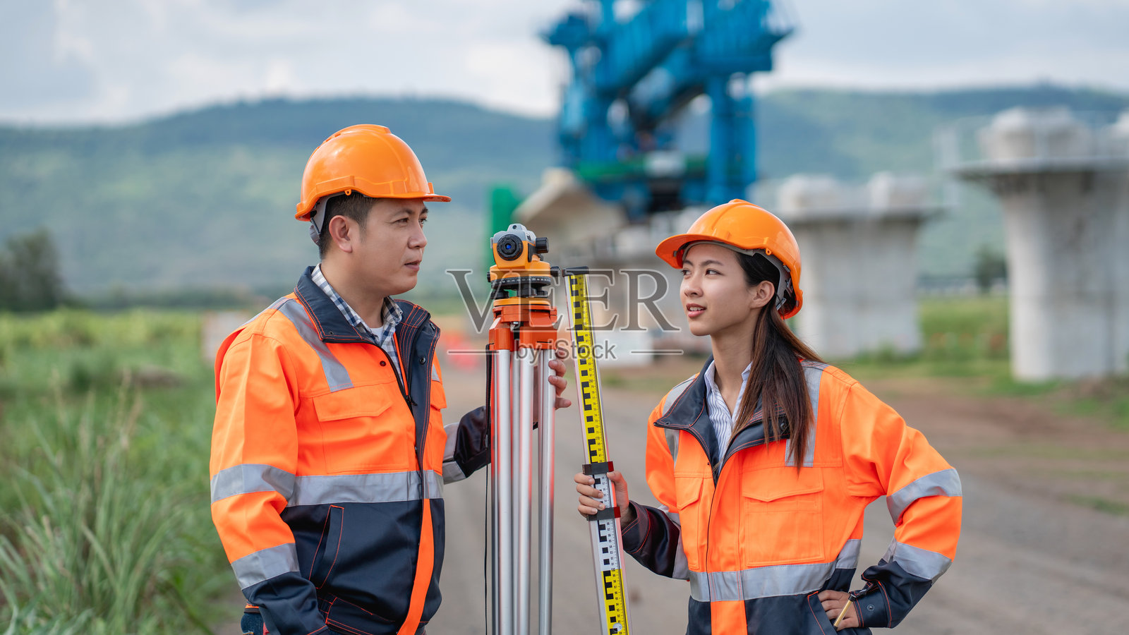 测量团队正在使用经纬仪和道路施工图纸进行工作。土木工程师在施工过程中使用测量工具进行测量。照片摄影图片