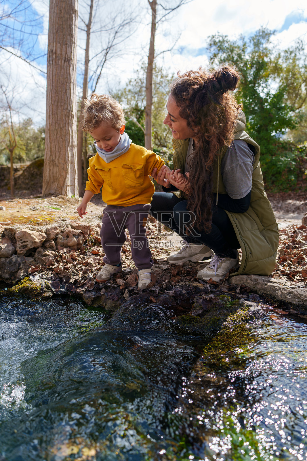 母亲和儿子在森林里的小河旁探索大自然照片摄影图片