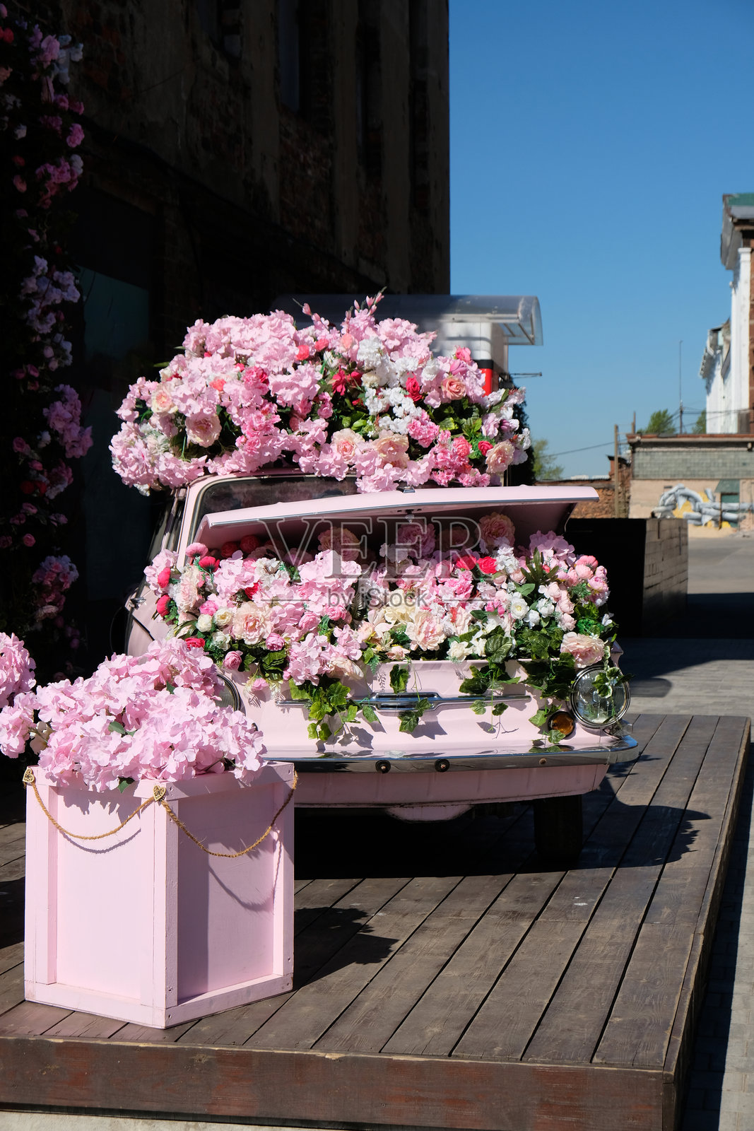 一辆粉色的旧车，装饰着粉色花朵，用作花店的广告照片摄影图片
