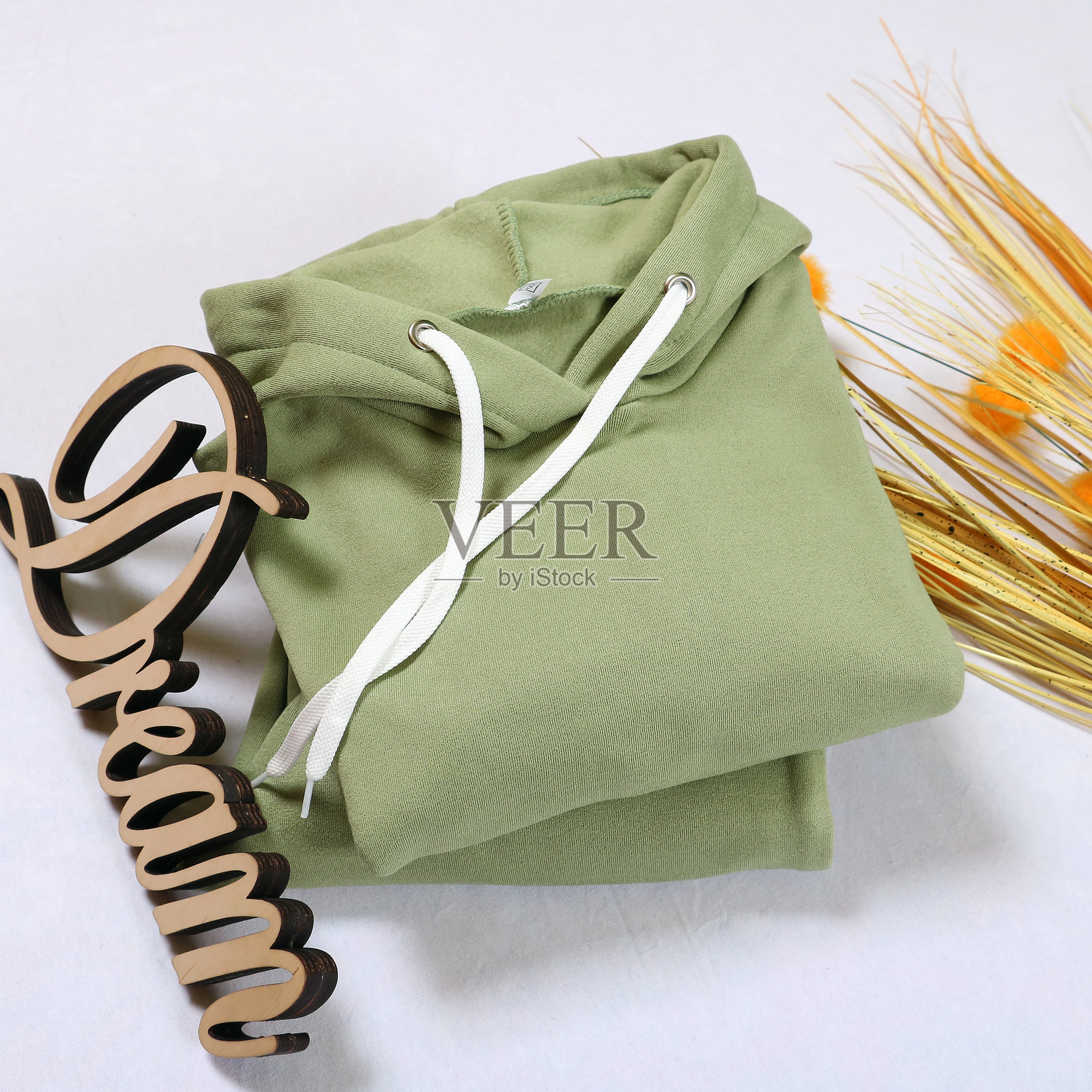 时尚的绿色运动服：一件带有袋鼠口袋的舒适连帽衫和带有袖口的抽绳运动裤。非常适合休闲穿着、运动和放松，兼具风格与舒适。照片摄影图片