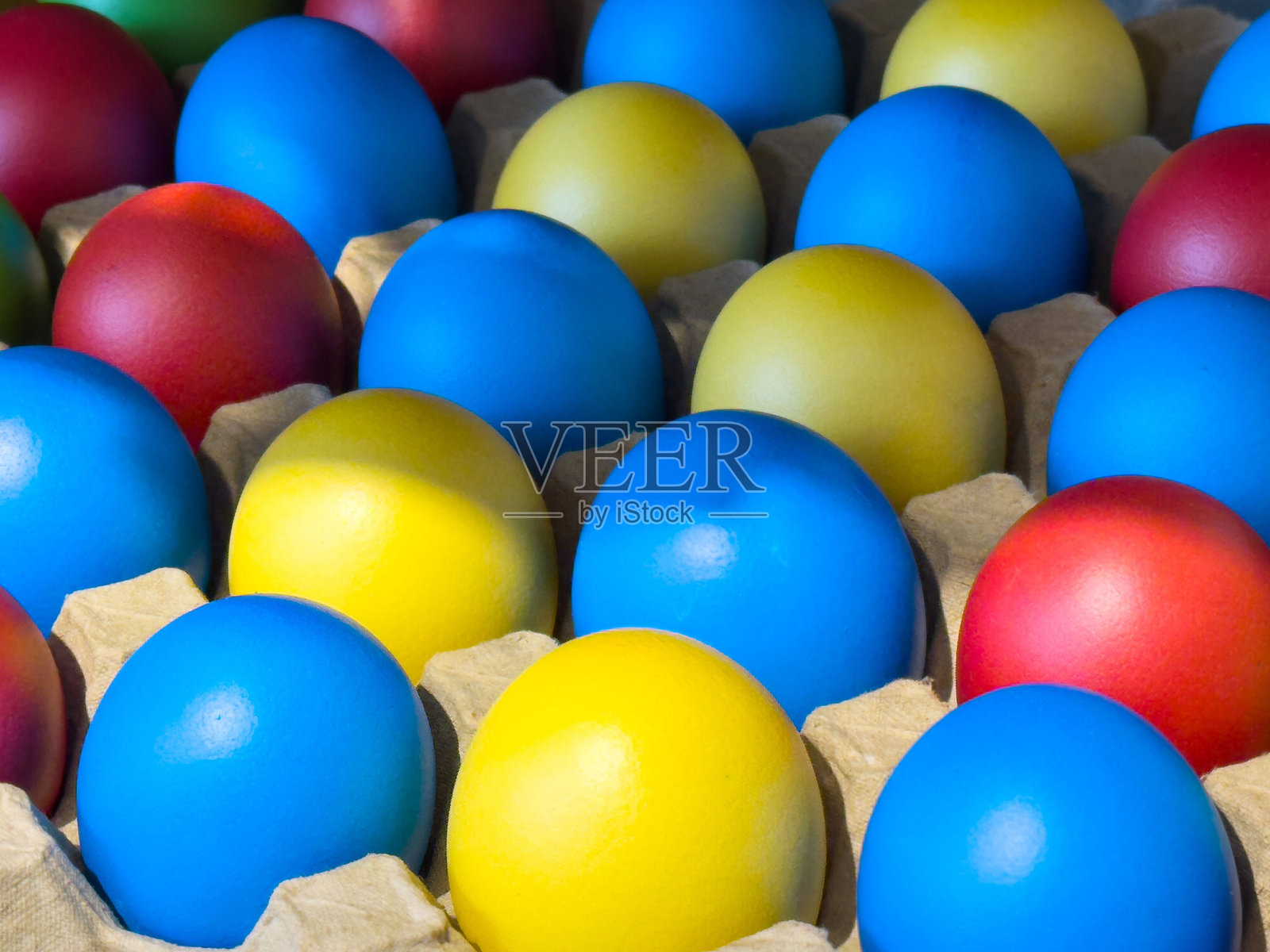 色彩鲜艳的黄色和蓝色鸡蛋放在纸箱托盘中，复活节概念照片摄影图片