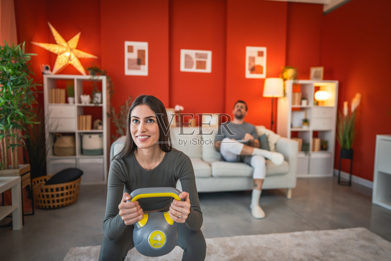 女性在家中使用壶铃做深蹲锻炼照片摄影图片