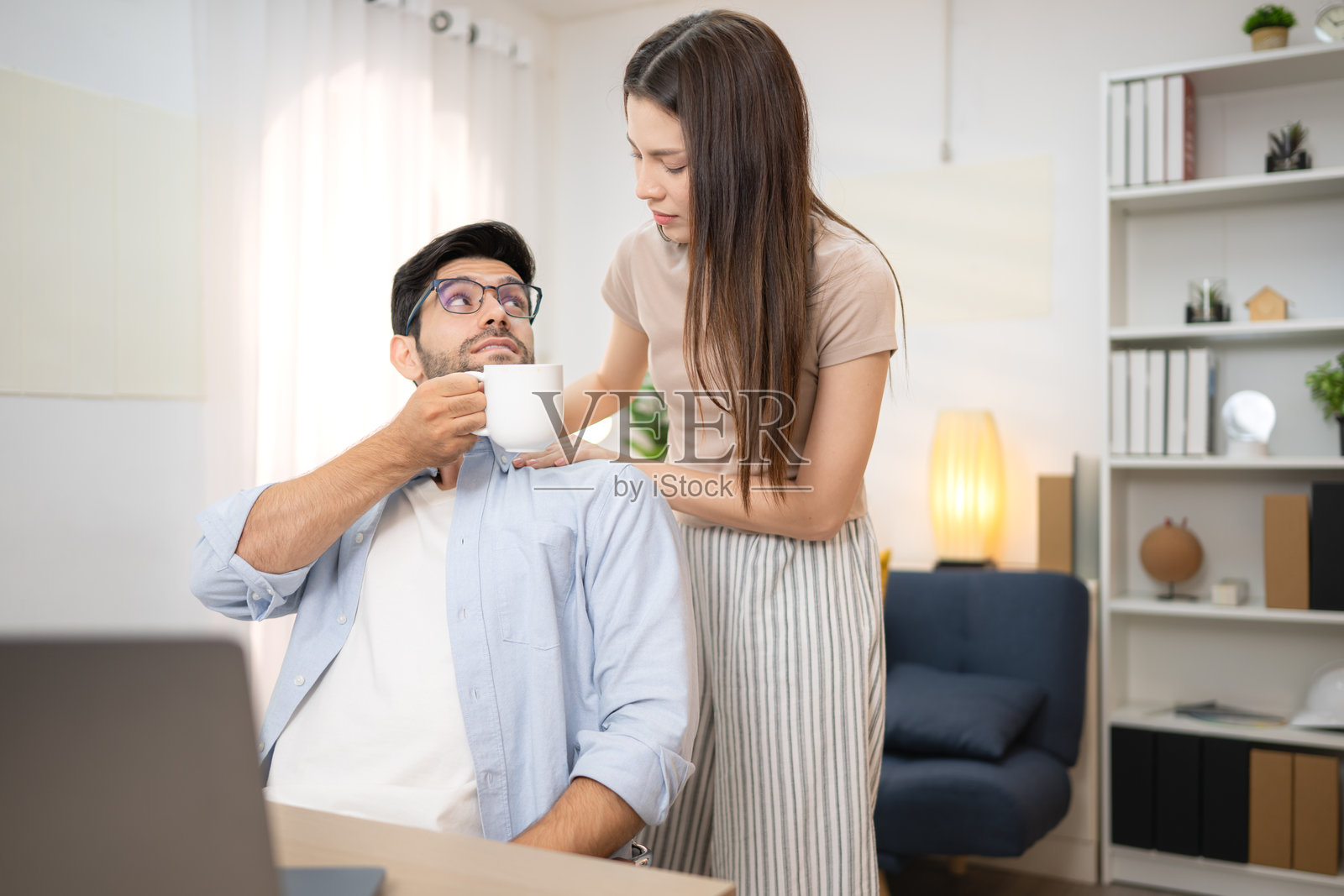 年轻自由职业者在家与女友一起用笔记本电脑在线工作，面带微笑。照片摄影图片