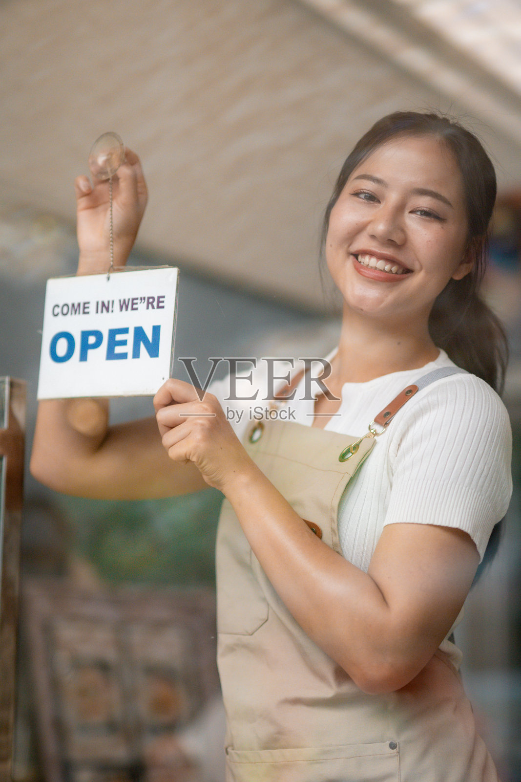 小企业主挂着开放标志，微笑的亚洲女服务员站在玻璃门入口附近照片摄影图片