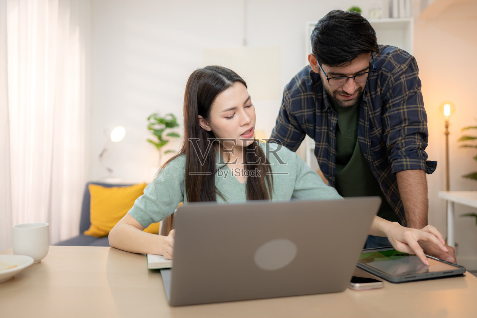 Portrait of a young freelancer smiling while working online via laptop at home with his boyfriend照片摄影图片
