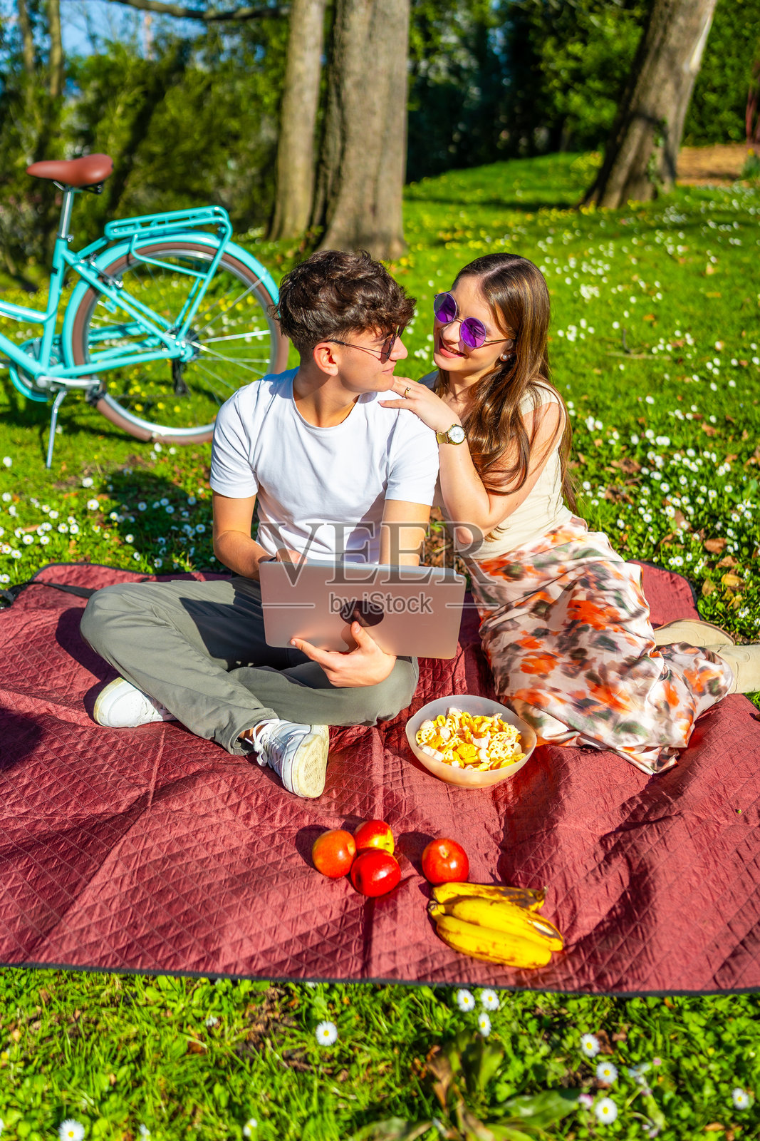 年轻情侣在公园享受野餐并观看笔记本电脑上的电影照片摄影图片