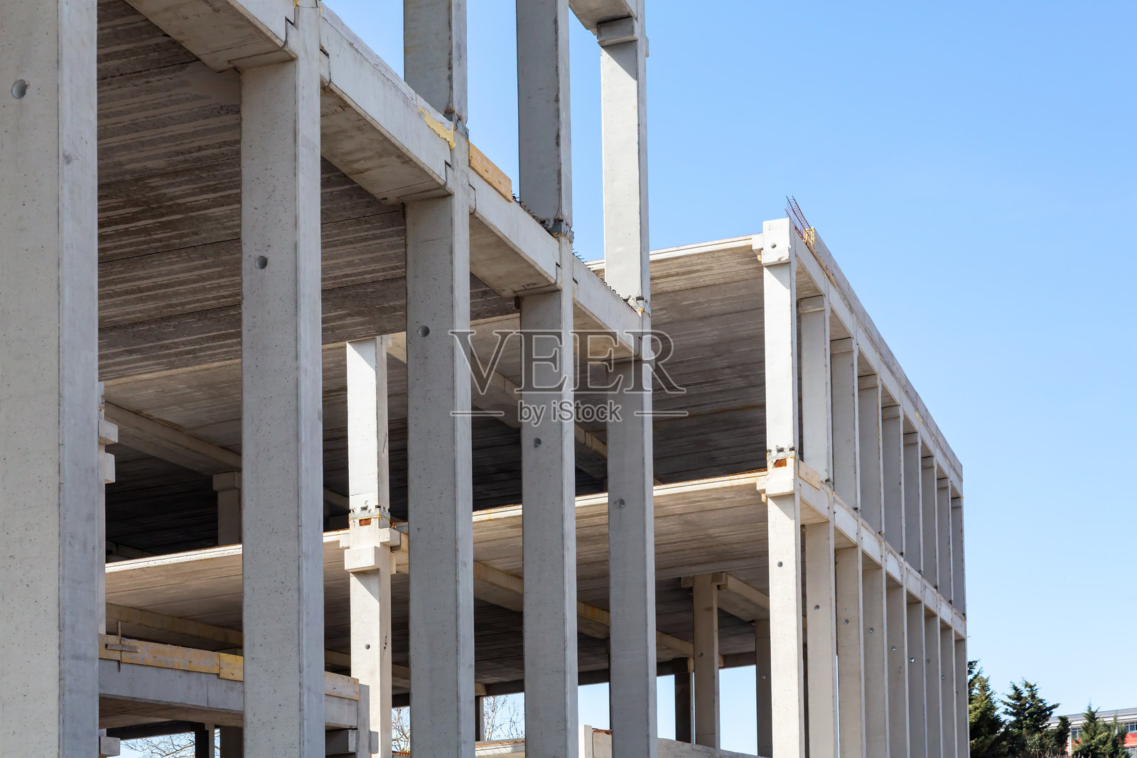 在晴朗的蓝天下，正在建设中的混凝土建筑，展示了现代建筑和结构设计。照片摄影图片