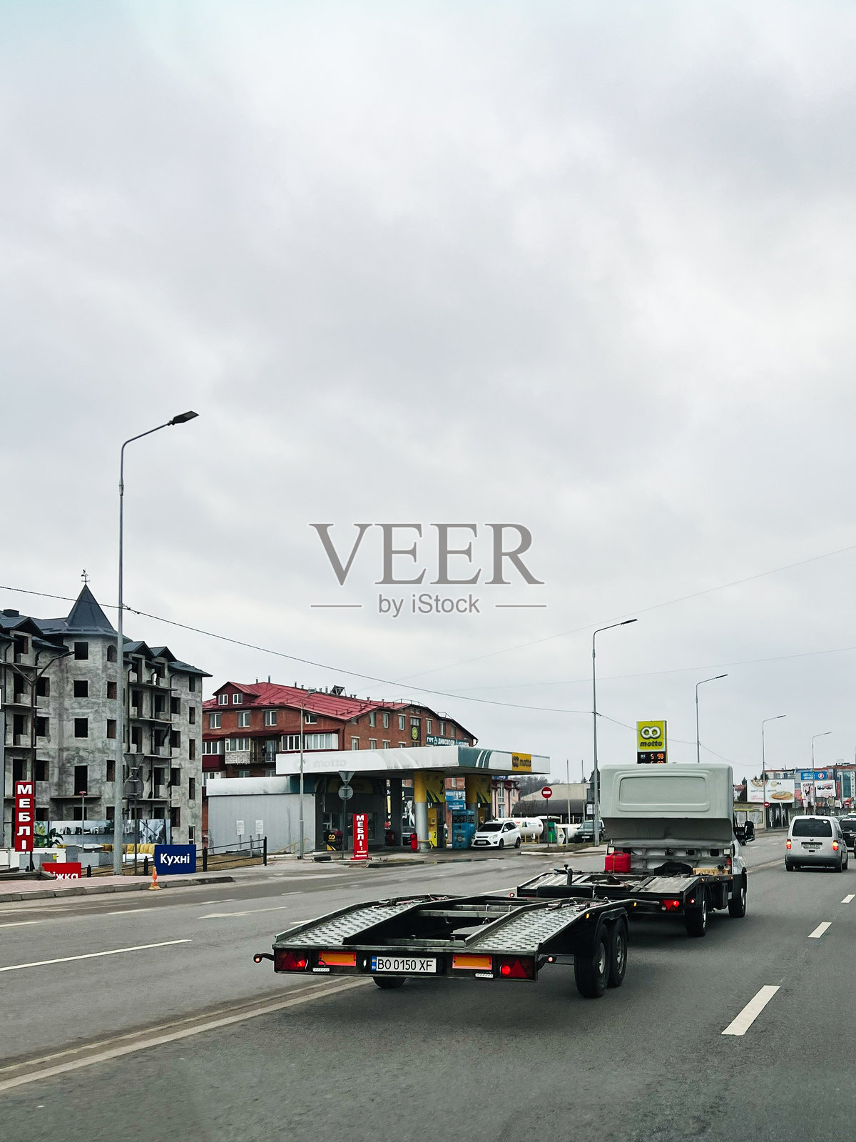 一条道路上，车辆和拖车经过住宅和商业建筑，天空阴云密布。照片摄影图片