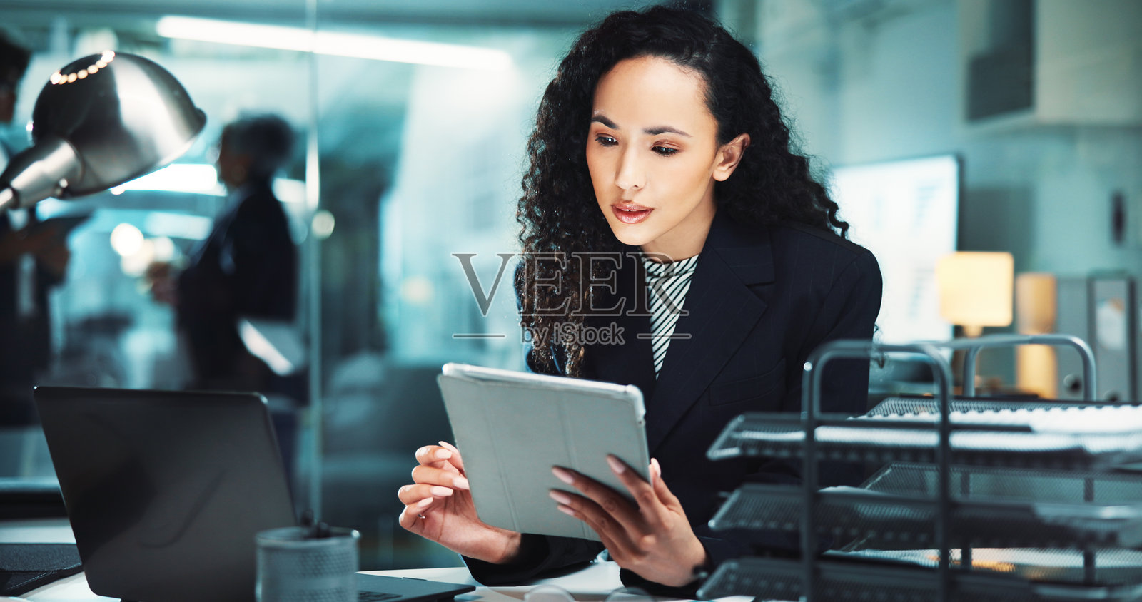 夜晚，女性使用平板电脑阅读新闻或进行财务管理，商业和预算审查。会计师在办公室进行技术和利润报告，以应对审计截止日期、税务合规或会计信息。照片摄影图片