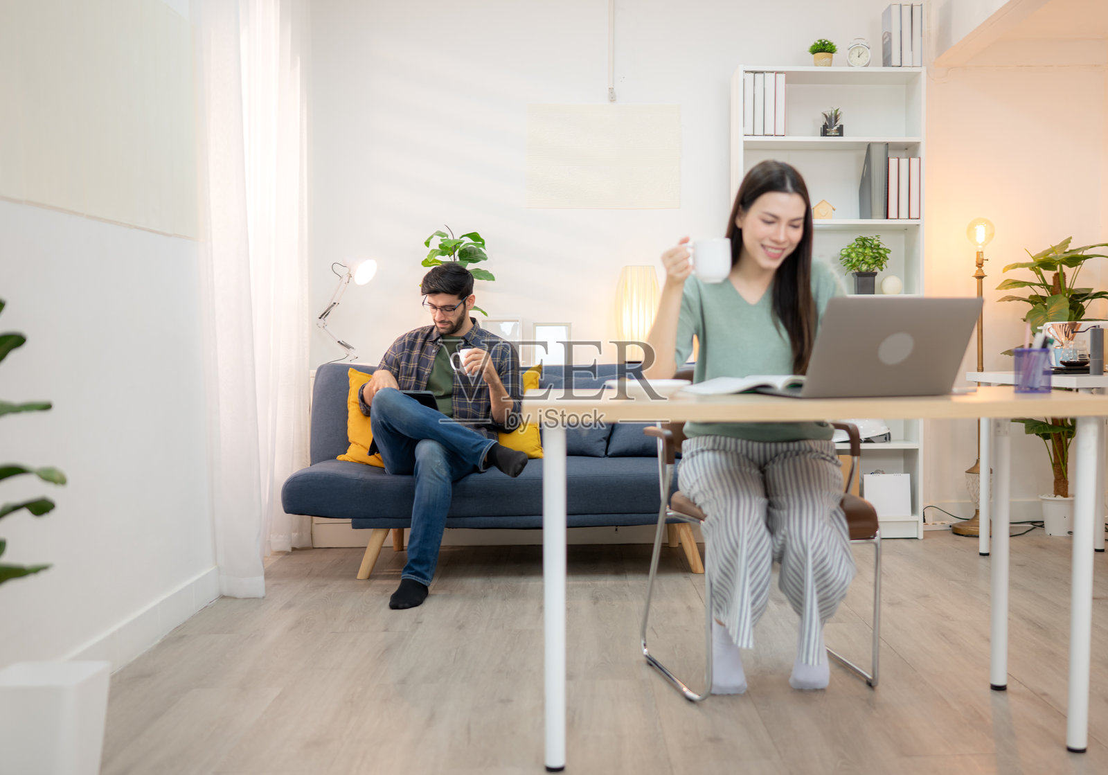 年轻自由职业者在家与男友一起用笔记本电脑在线工作，面带微笑。照片摄影图片