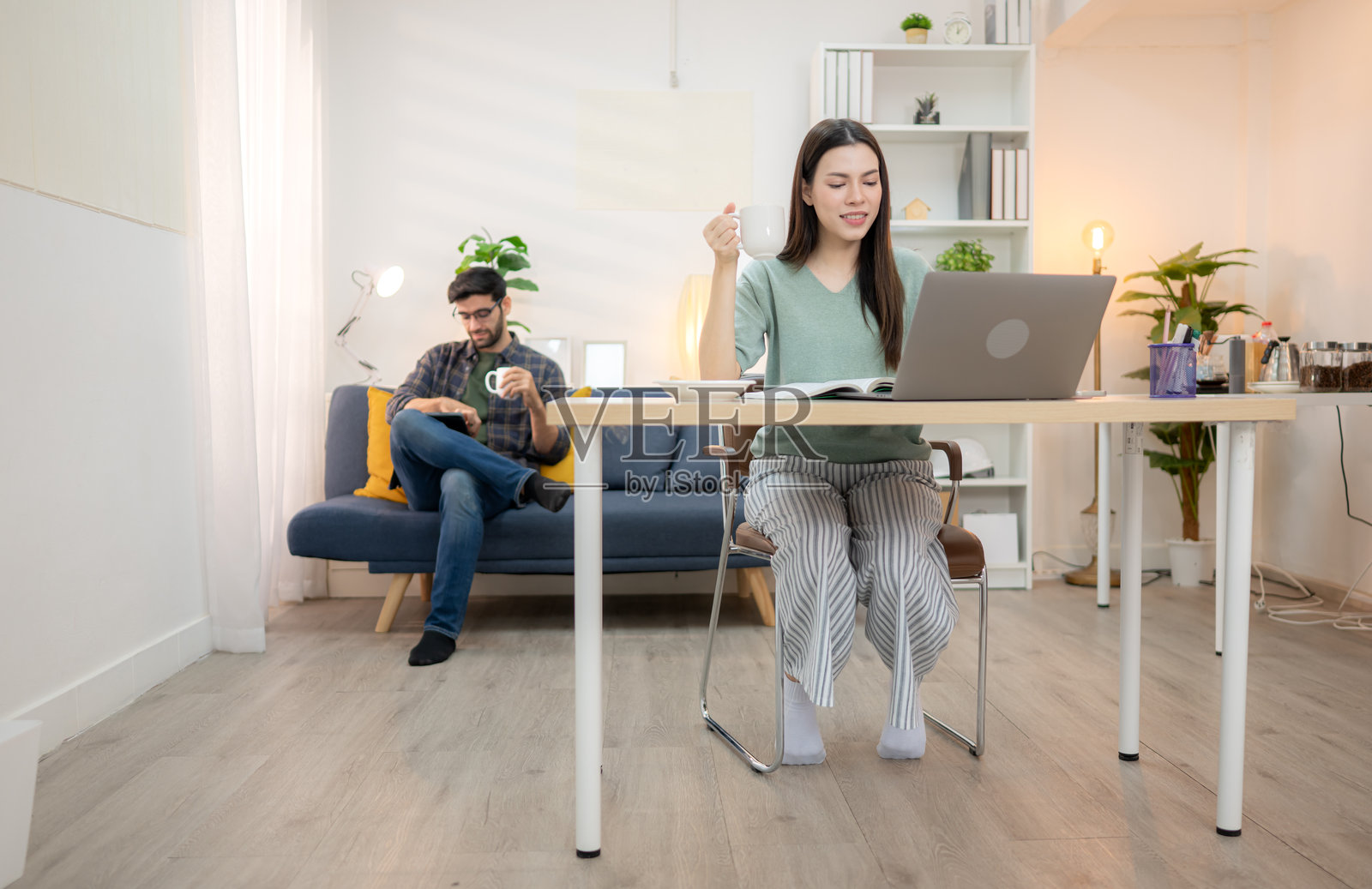 年轻自由职业者在家与男友一起用笔记本电脑在线工作，面带微笑。照片摄影图片