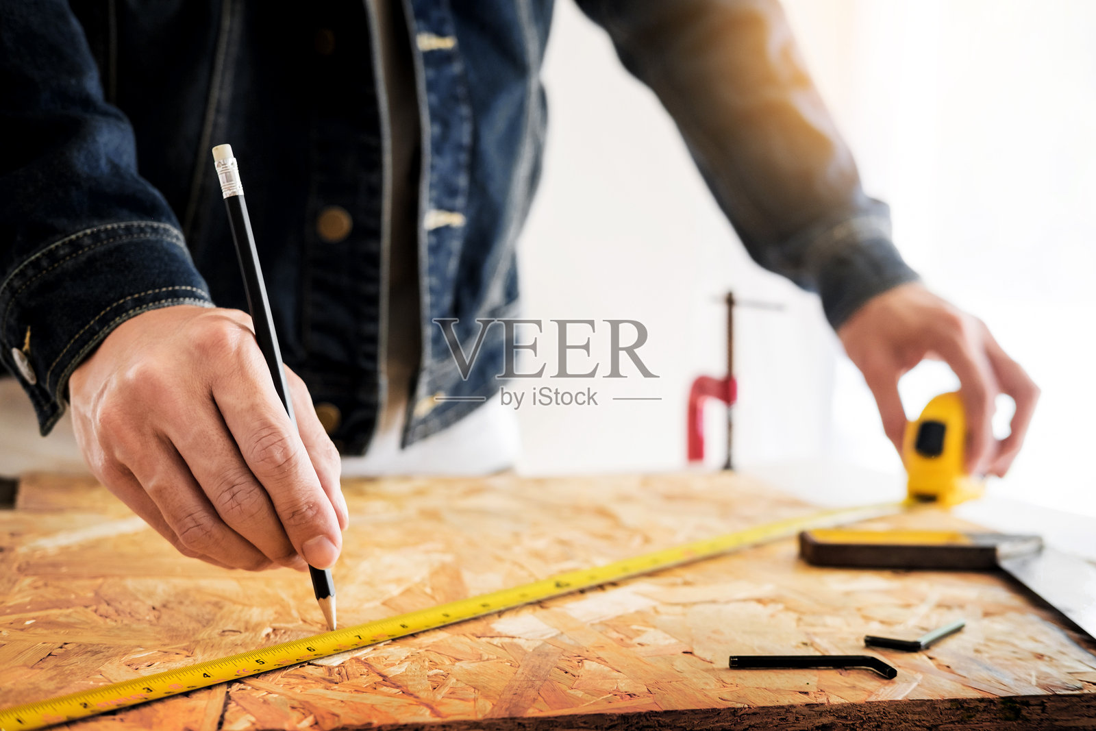 男子在白色背景下测量木材的中部照片摄影图片