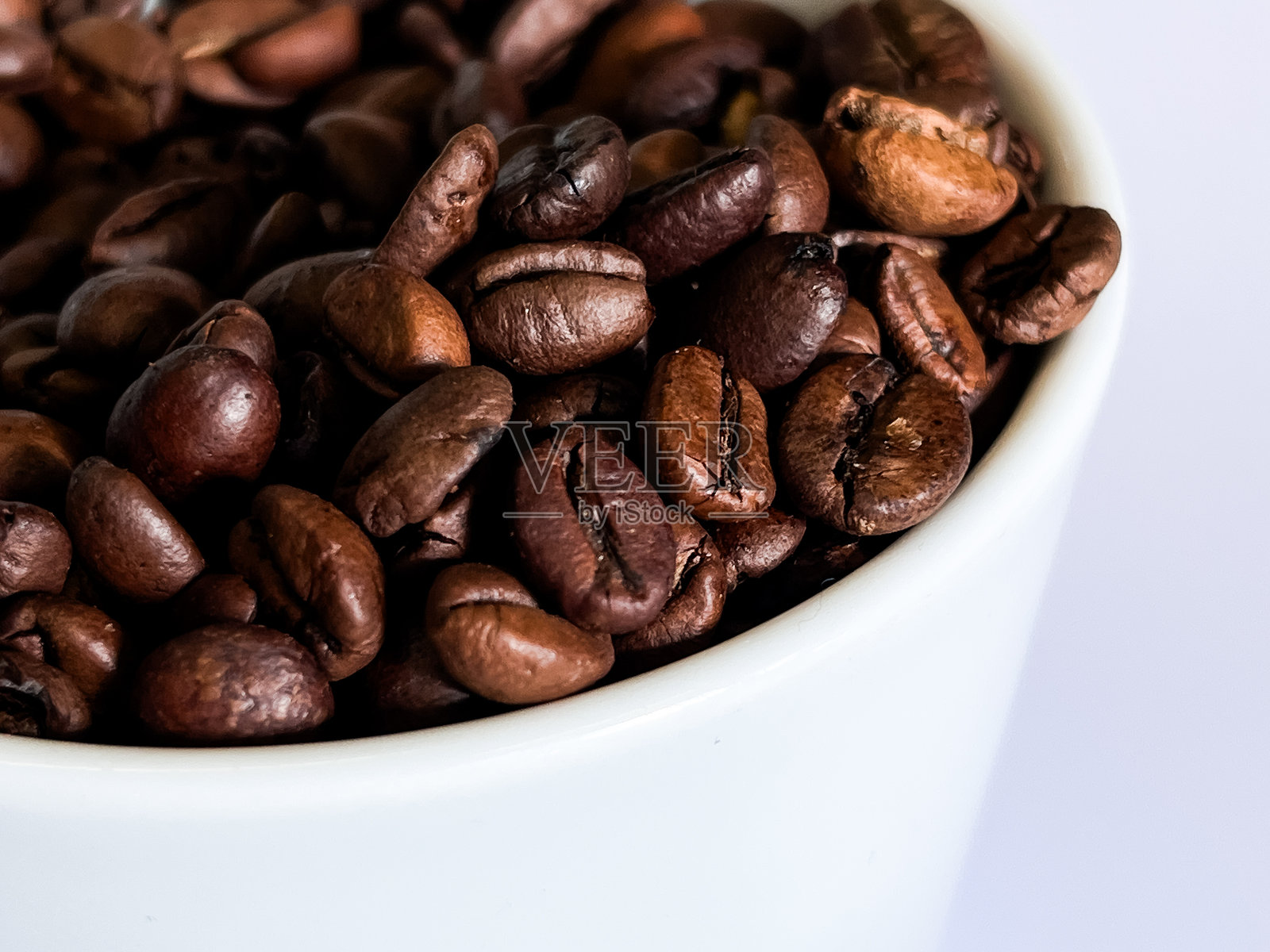 白色杯子里的咖啡豆堆。照片摄影图片