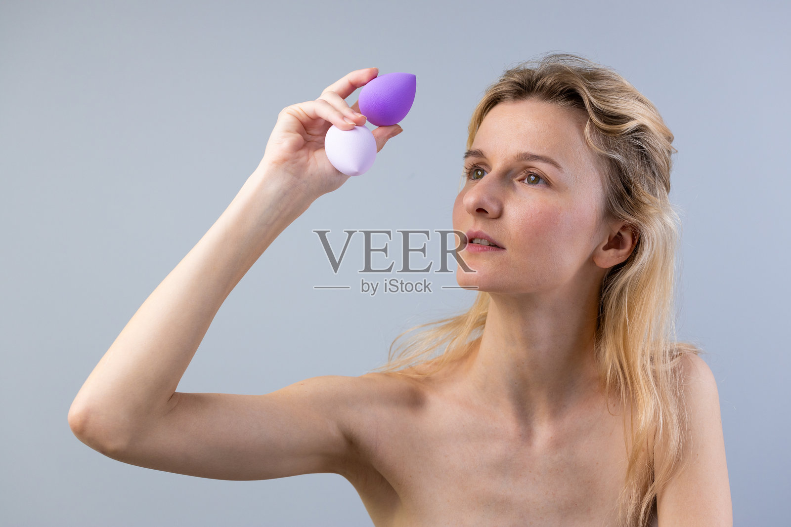 女性检查化妆工具：在自然光环境中，特写展示完美妆容和肌肤效果的美妆海绵照片摄影图片