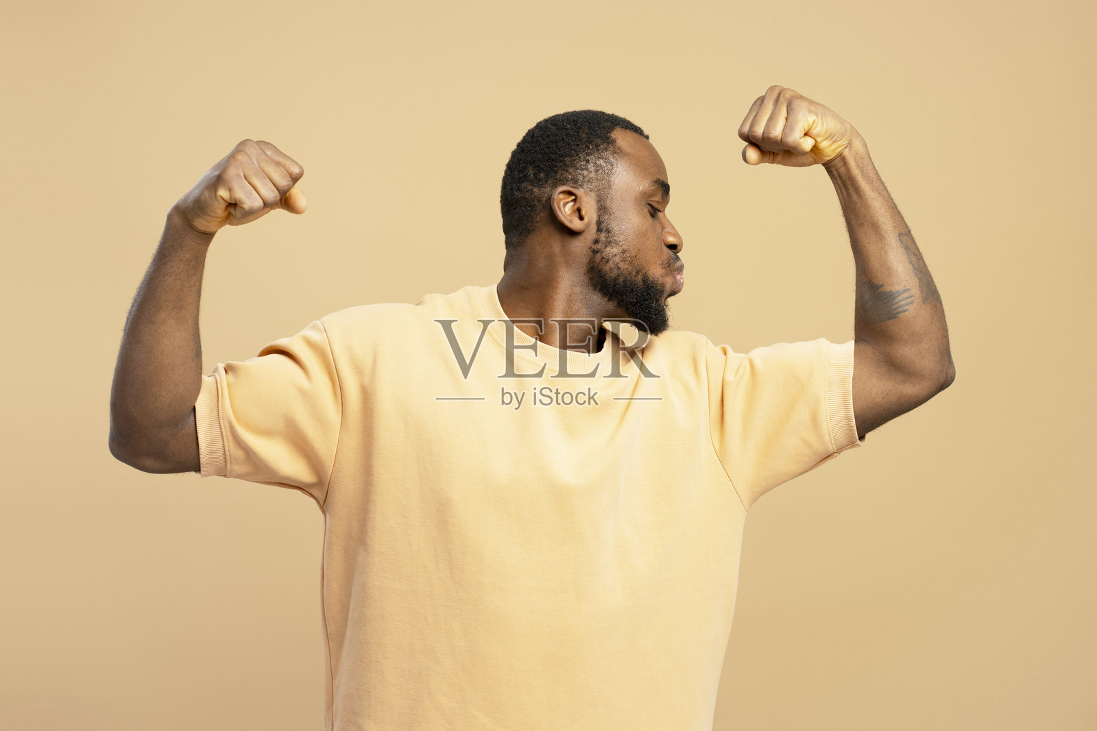 年轻男子在展示二头肌并亲吻它们照片摄影图片