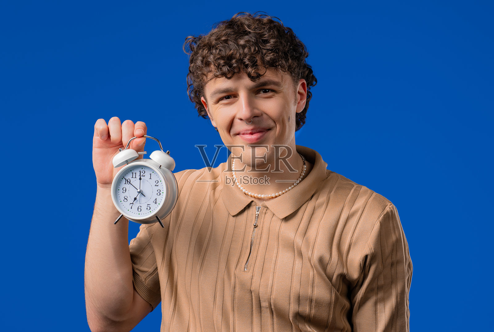 快乐的男人与闹钟在蓝色背景上。迟到的早晨，周末，终于。照片摄影图片