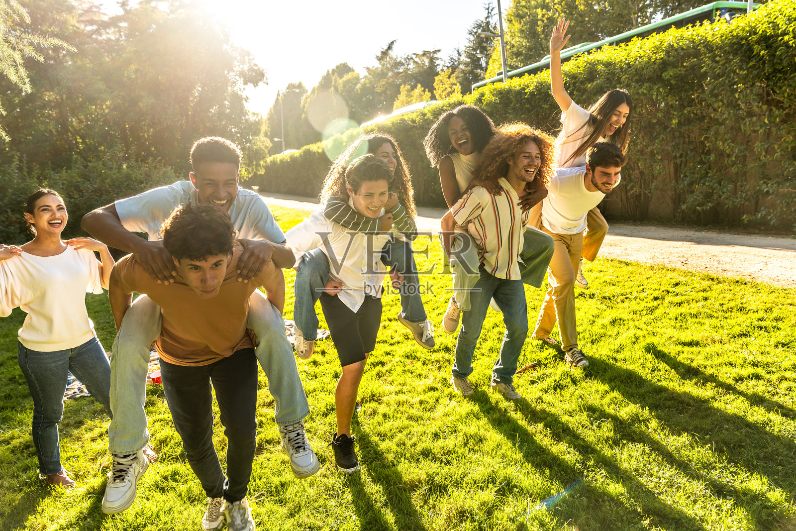 快乐的朋友们在阳光明媚的公园里背着彼此，享受着美好的时光照片摄影图片