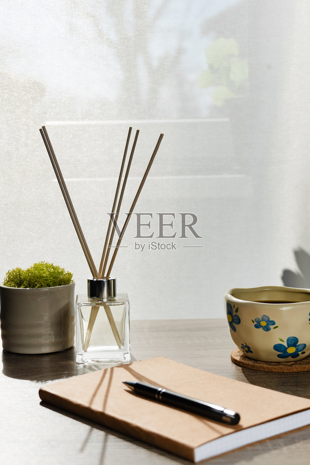 极简桌面布置，配有盆栽植物、香薰扩散器和陶瓷杯照片摄影图片