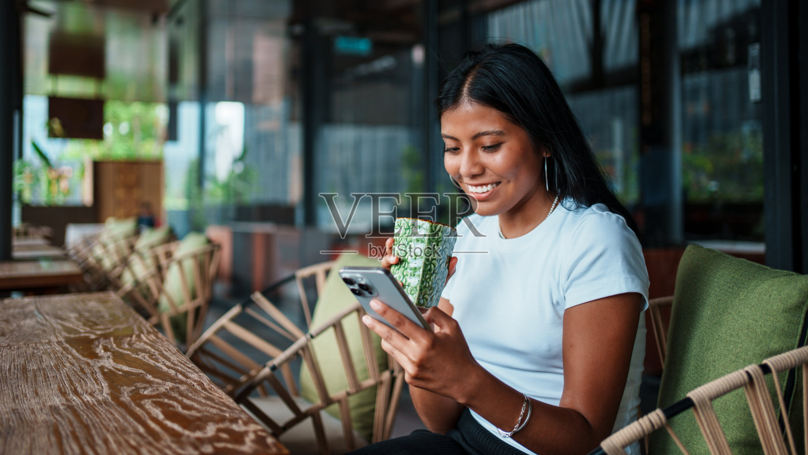 年轻女性在现代咖啡馆享受饮品并使用手机照片摄影图片