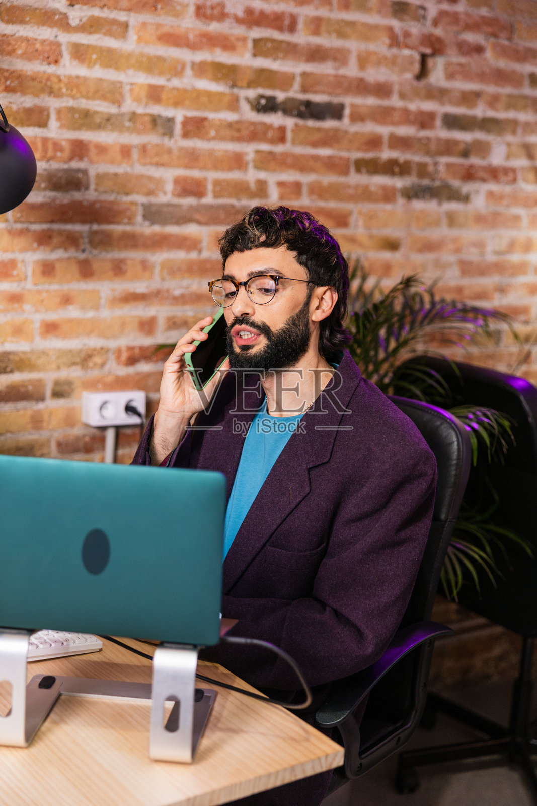 年轻企业家一边打电话一边使用笔记本电脑管理业务照片摄影图片