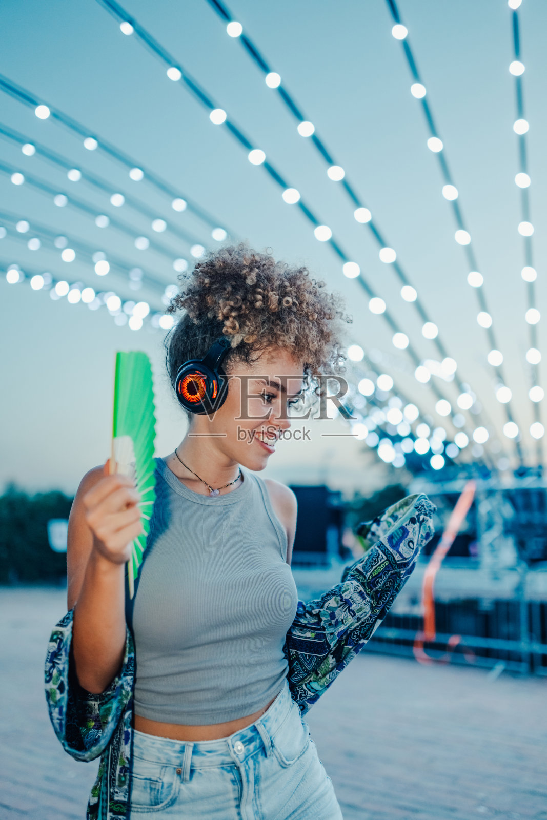 年轻女性在音乐节上戴着耳机和扇子跳舞照片摄影图片