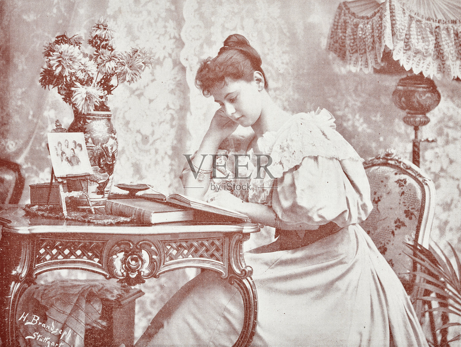 坐在满是书籍、花朵和图片的桌子旁的读书女士插画图片素材