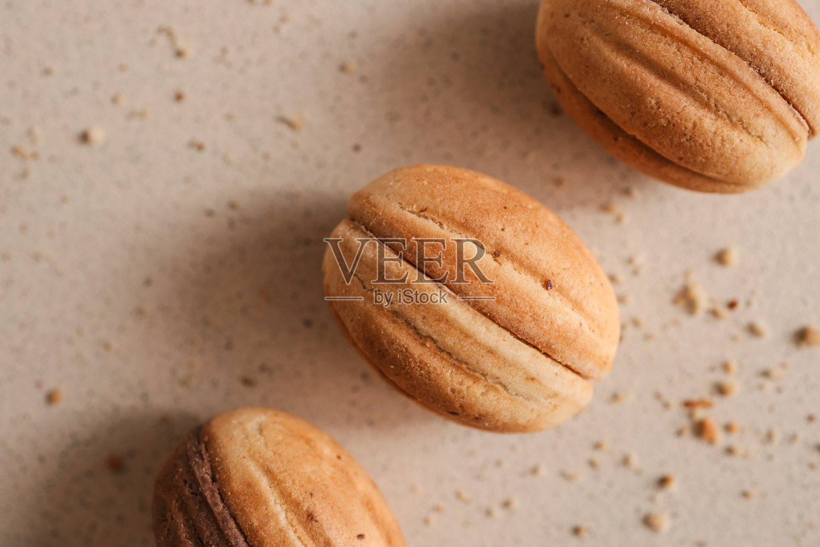 坚果形状的饼干，夹有焦糖馅，背景为米色。自制的黄油饼干特写，撒满了碎屑。传统的甜点，适合茶或咖啡时享用。照片摄影图片