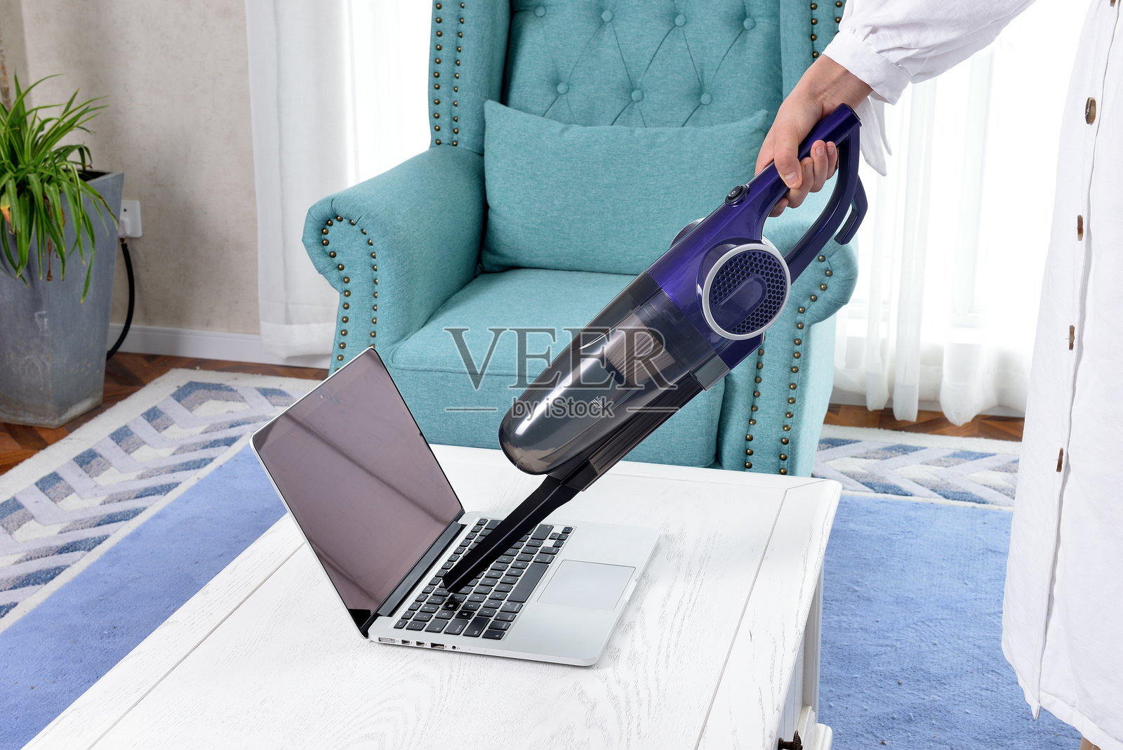 家庭主妇用电动吸尘器清洁笔记本电脑键盘照片摄影图片