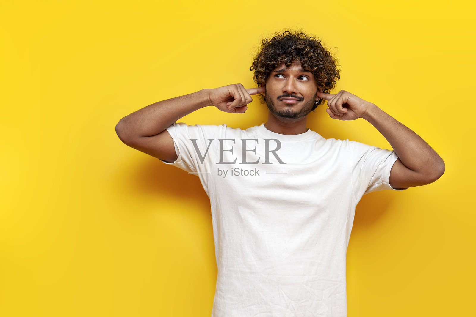 年轻的印度男孩在黄色背景下避开并忽视噪音照片摄影图片