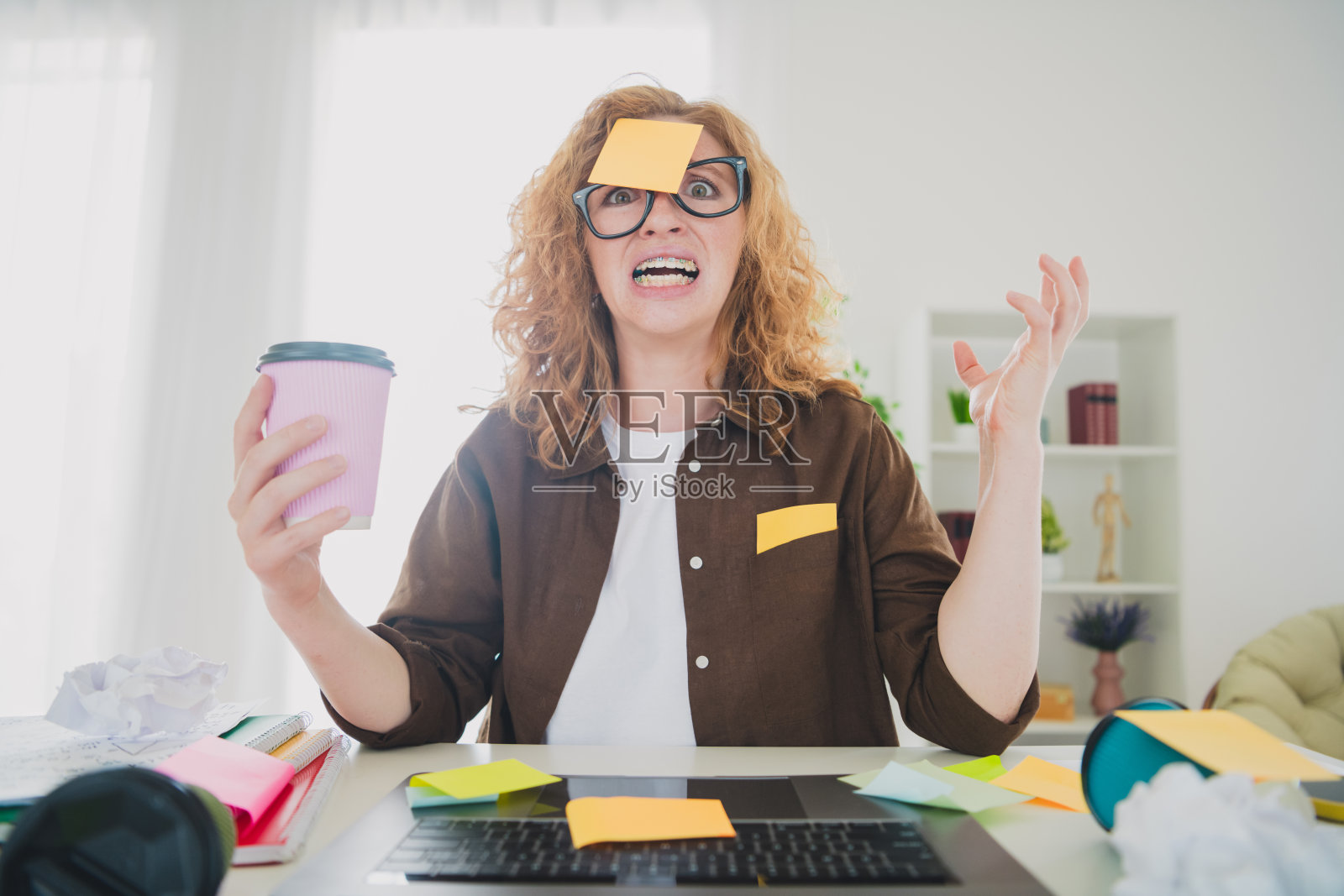 焦虑、紧张、负担过重的女性坐在桌子前，努力在家中室内工作。照片摄影图片