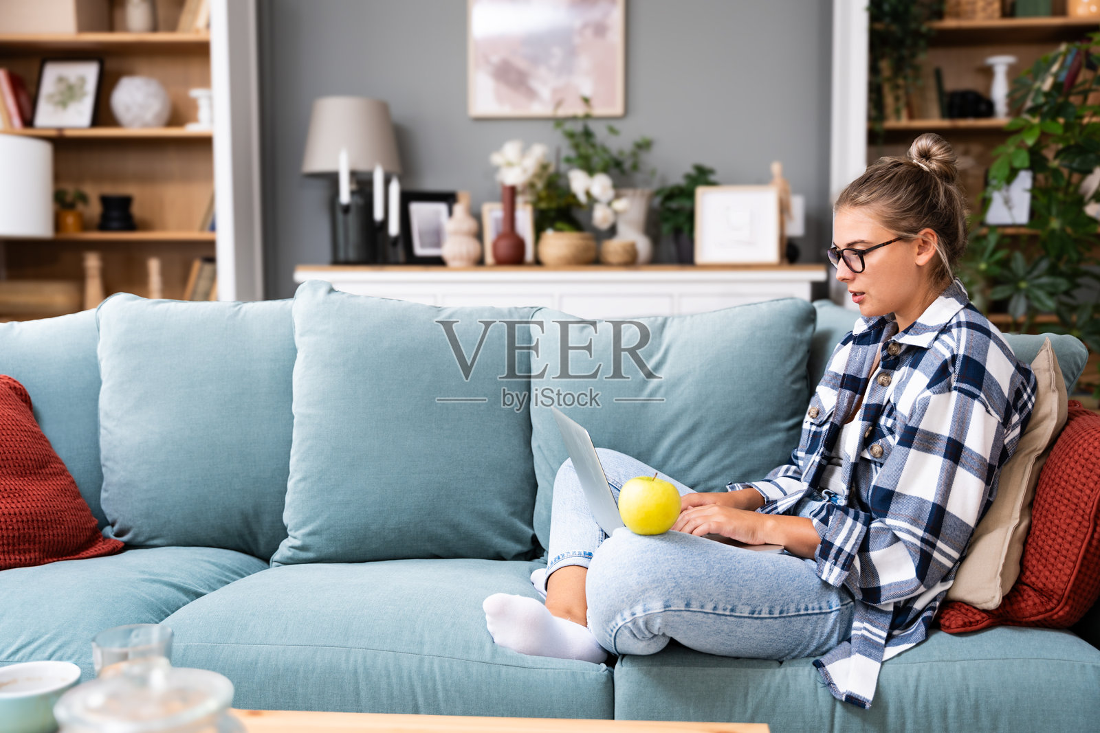 满意的女学生在舒适的沙发上放松，使用笔记本电脑在家中，快乐的女孩与朋友在社交网络上聊天，度过懒散的周末，观看电影，在线购物，写电子邮件。照片摄影图片