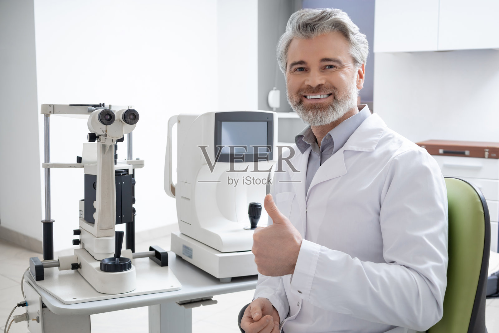 灰发男眼科医生在诊所工作照片摄影图片