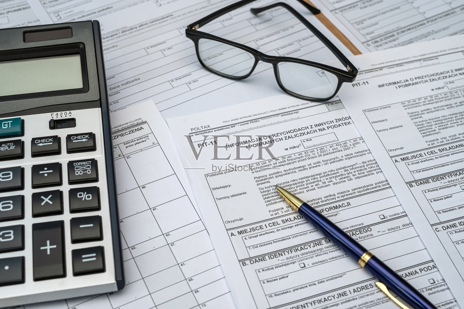 准备填写的波兰 PIT 11 37 38 税表，桌上有钢笔、计算器和眼镜。照片摄影图片