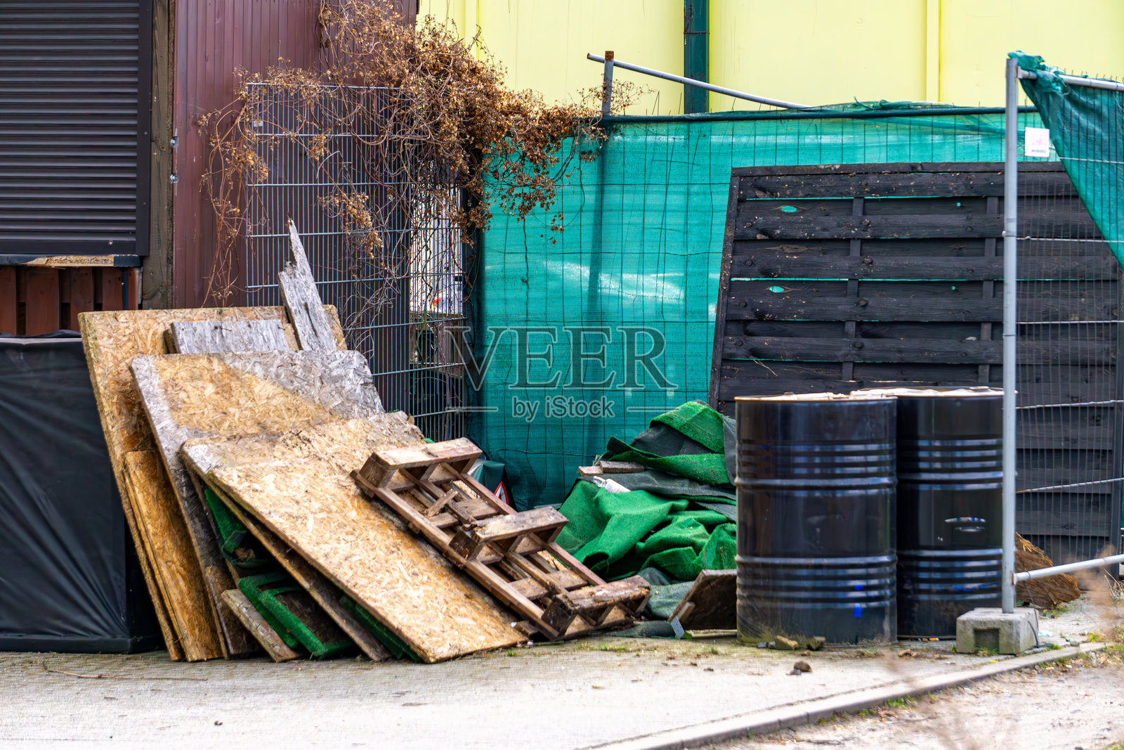 餐厅后面堆放着建筑垃圾，包括胶合板废料、破损的运输托盘和黑色桶。照片摄影图片