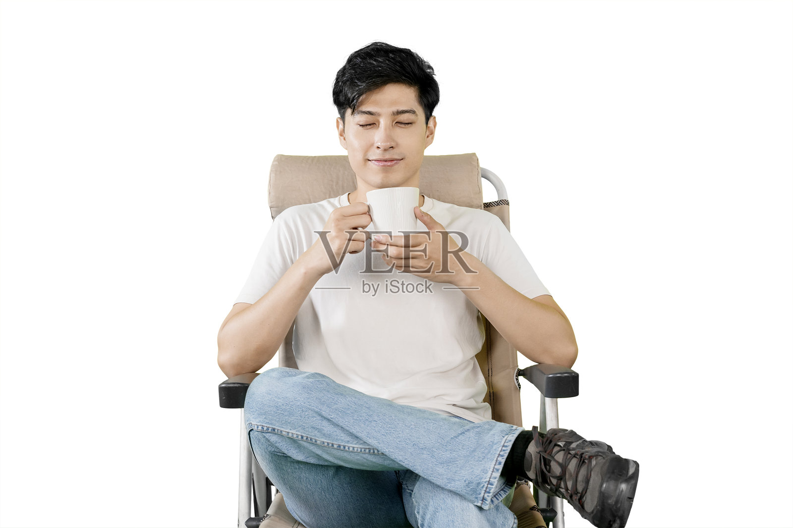 年轻男子舒适地坐着，闭着眼睛享受一杯咖啡。照片摄影图片