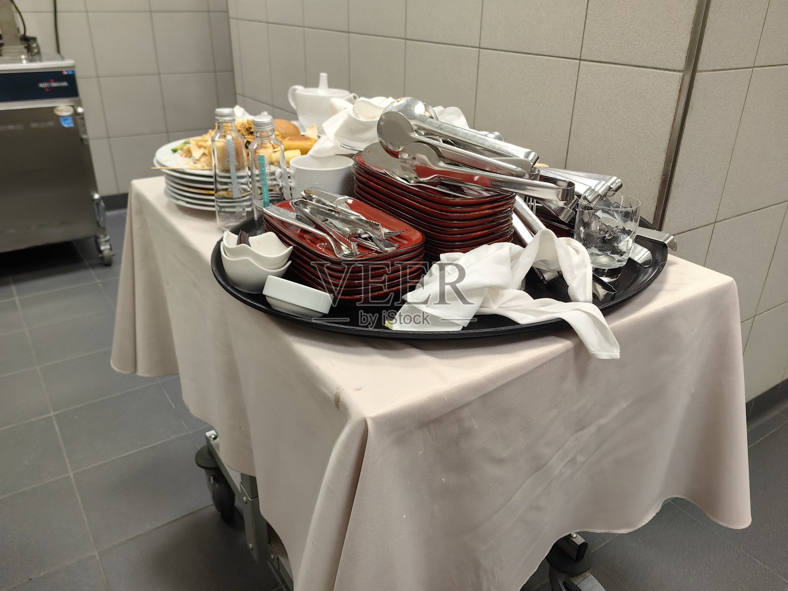 餐厅食物推车上的清洁盘子和玻璃杯。照片摄影图片