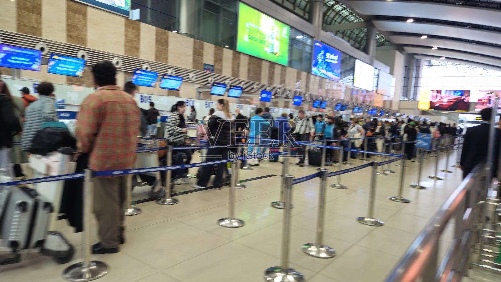 繁忙的机场值机区，乘客和航空公司工作人员在多个柜台前忙碌，准备登机。照片摄影图片