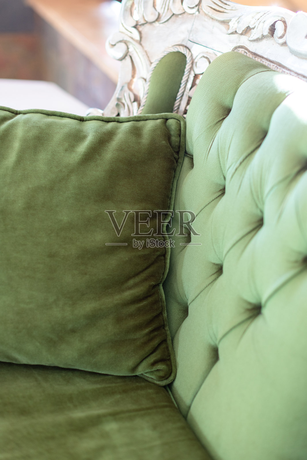 大型巴洛克风格的绿色天鹅绒扶手椅特写，带有雕刻木质细节和靠垫照片摄影图片