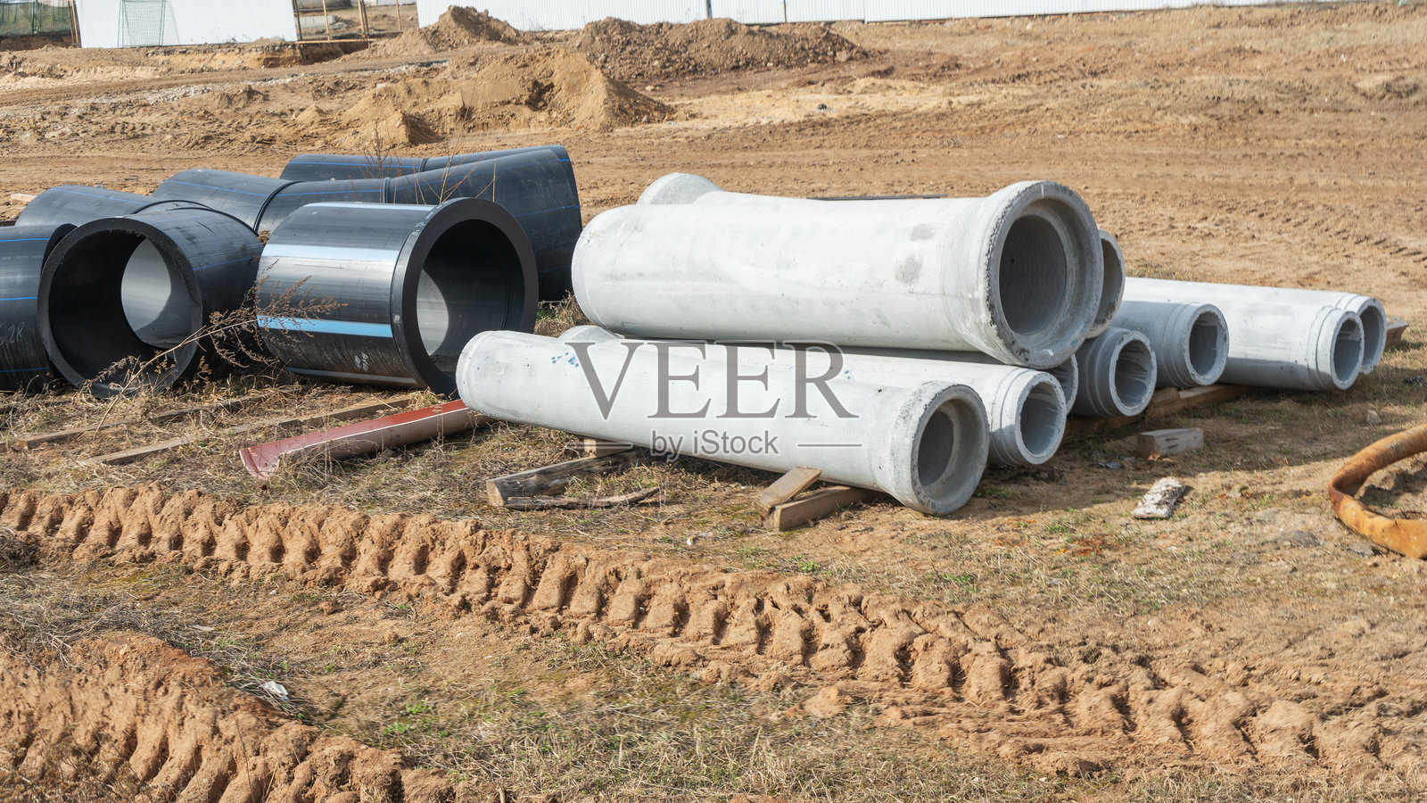 建筑工地展示各种直径的聚乙烯和混凝土管道，用于供水。这些耐用的管道确保高效的水分配和基础设施的可靠性。照片摄影图片