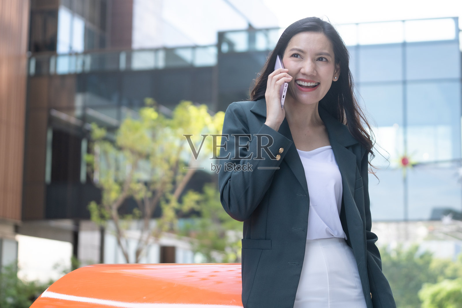 在城市环境中，户外工作的亚洲女高管正在打电话。照片摄影图片