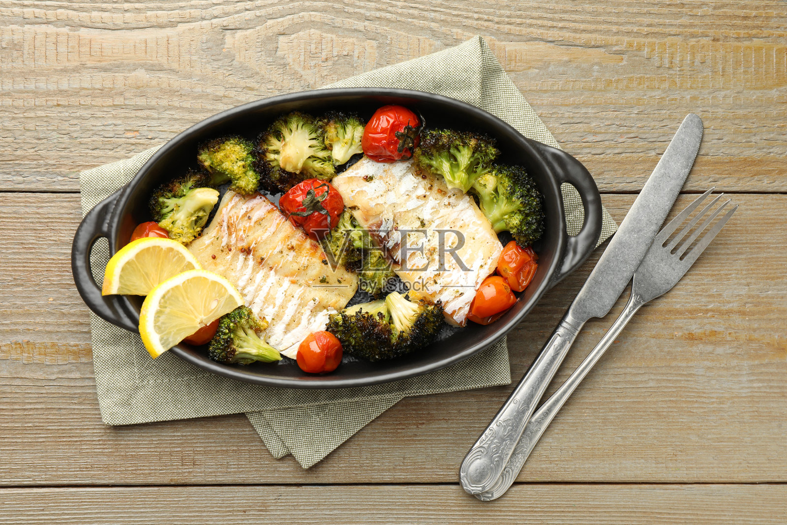 美味的鳕鱼与蔬菜一起烹饪，摆放在木桌上，俯视图。照片摄影图片