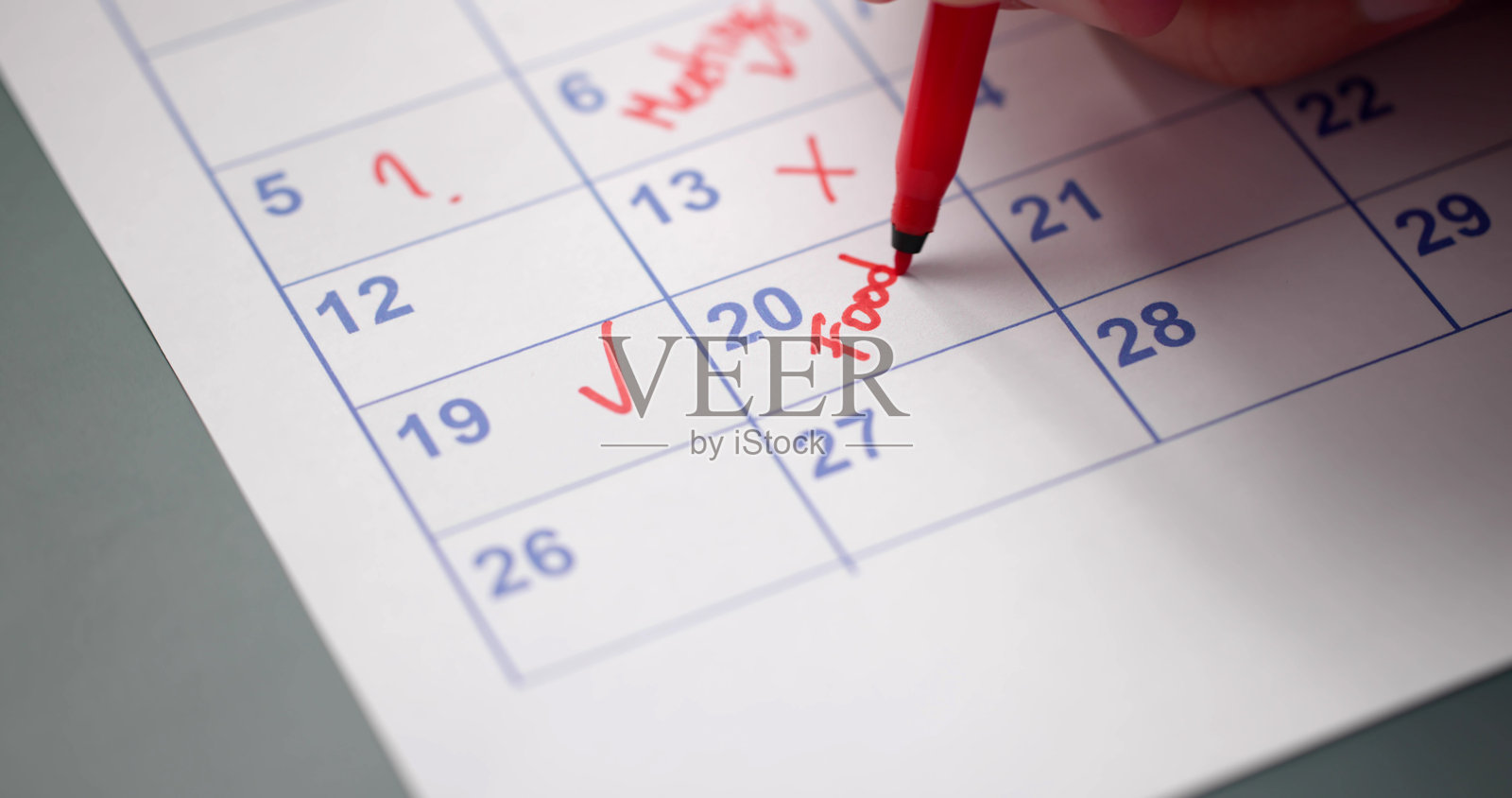 日历截止日期。年轻男子手持钢笔在标记。照片摄影图片