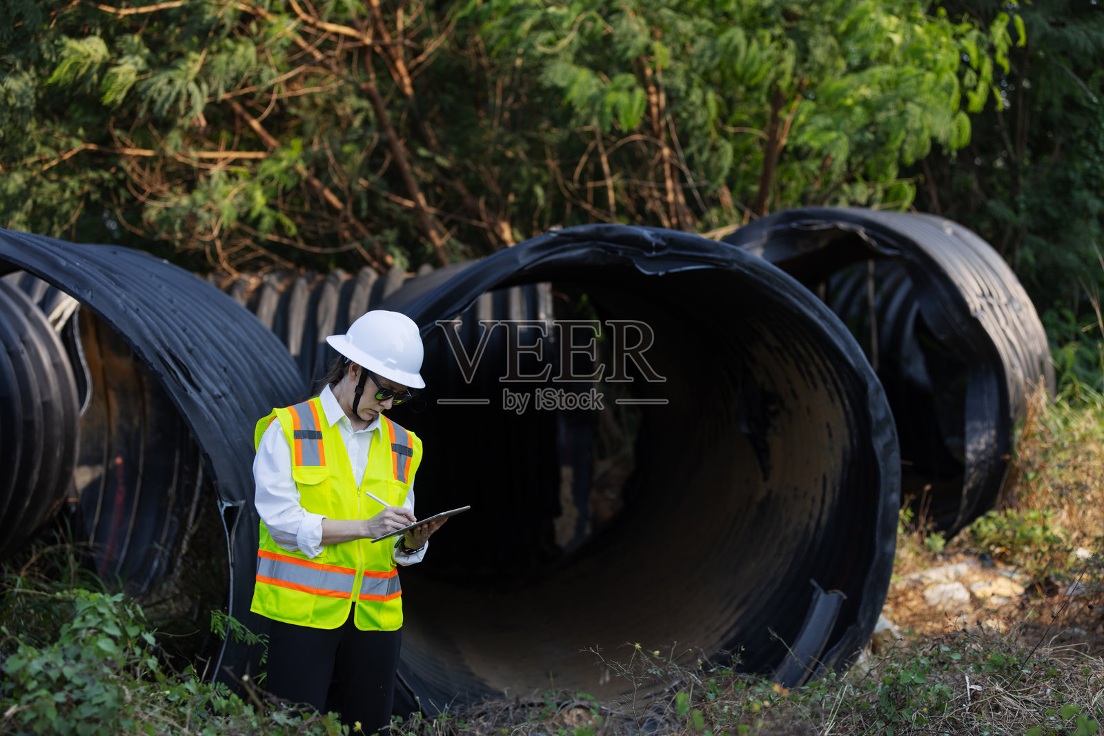 一位女性工程师在户外检查受损的大型排水管。照片摄影图片