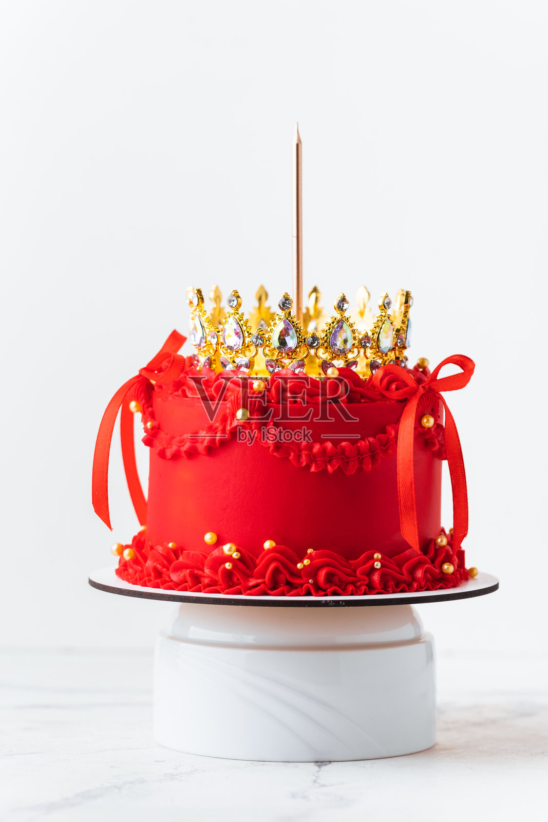 美丽的女王或公主主题红色蛋糕。奢华的兰贝斯风格生日蛋糕，装饰有复古奶油花纹和金色皇冠。白色背景。照片摄影图片