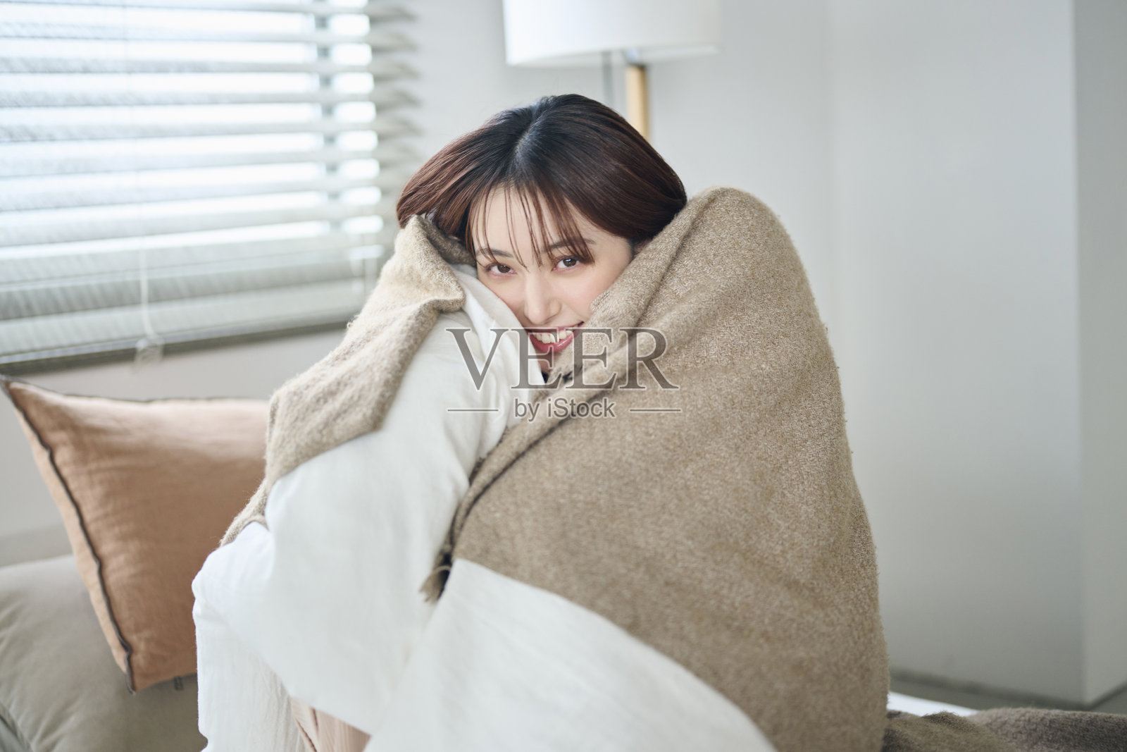 一位20多岁的女性裹在床上的被褥里照片摄影图片