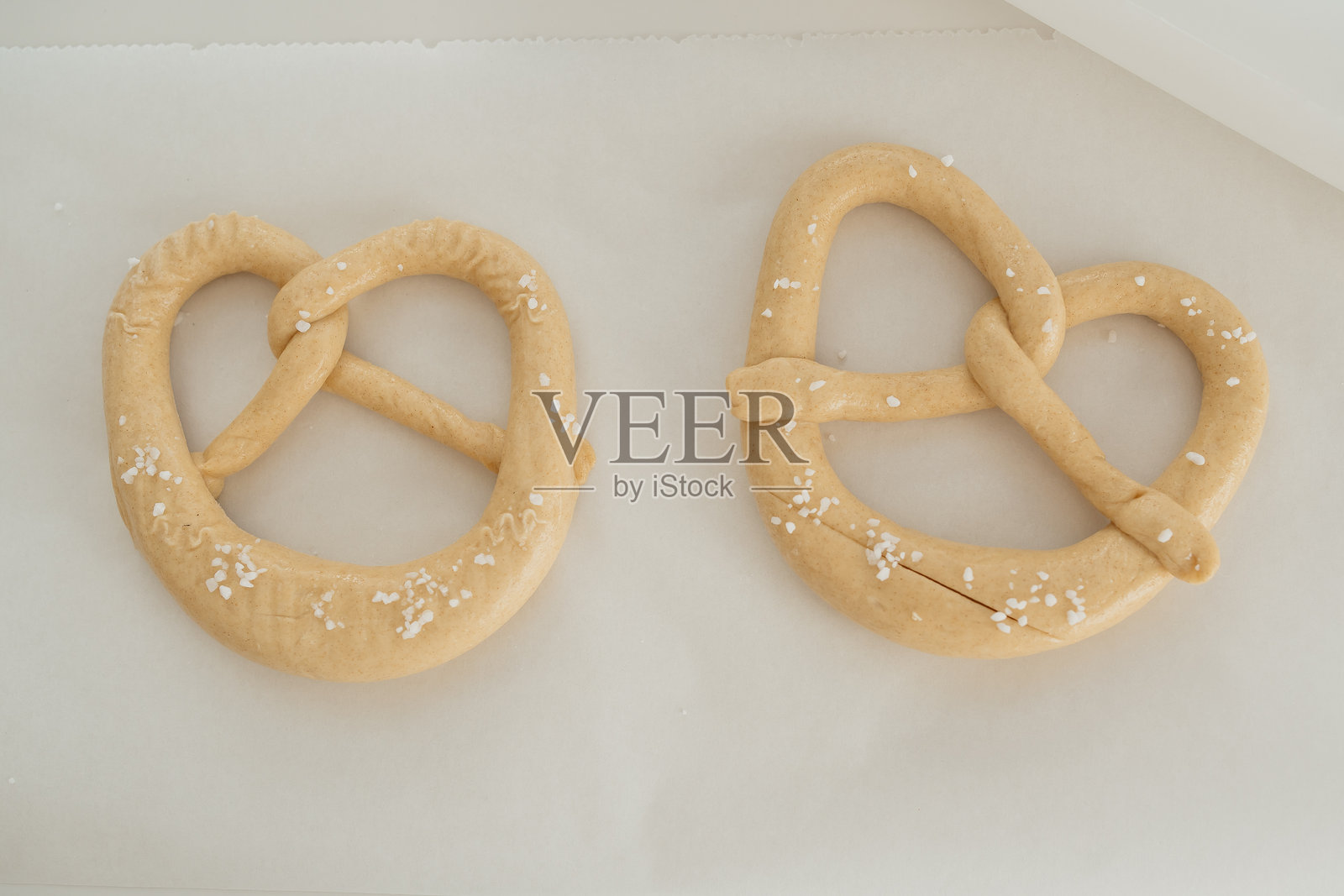 新鲜出炉的盐味椒盐卷饼放在烘焙纸上照片摄影图片