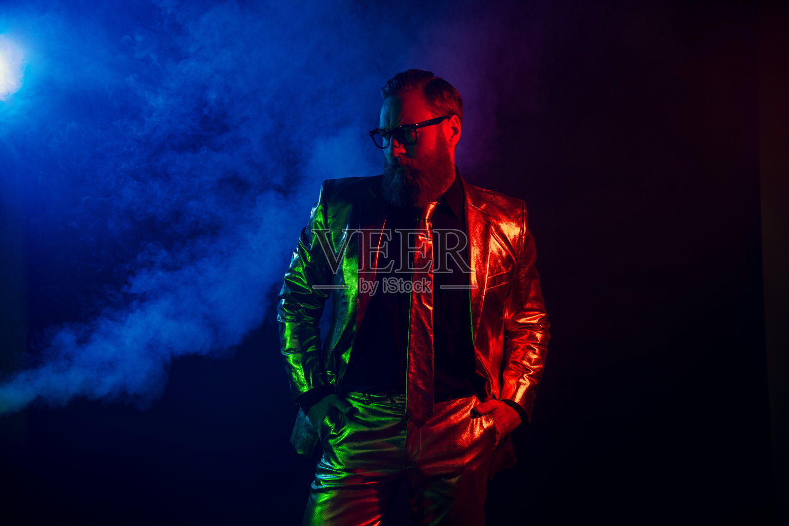 充满魅力的男子，穿着光泽感西装，佩戴复古眼镜，沐浴在霓虹光芒中照片摄影图片