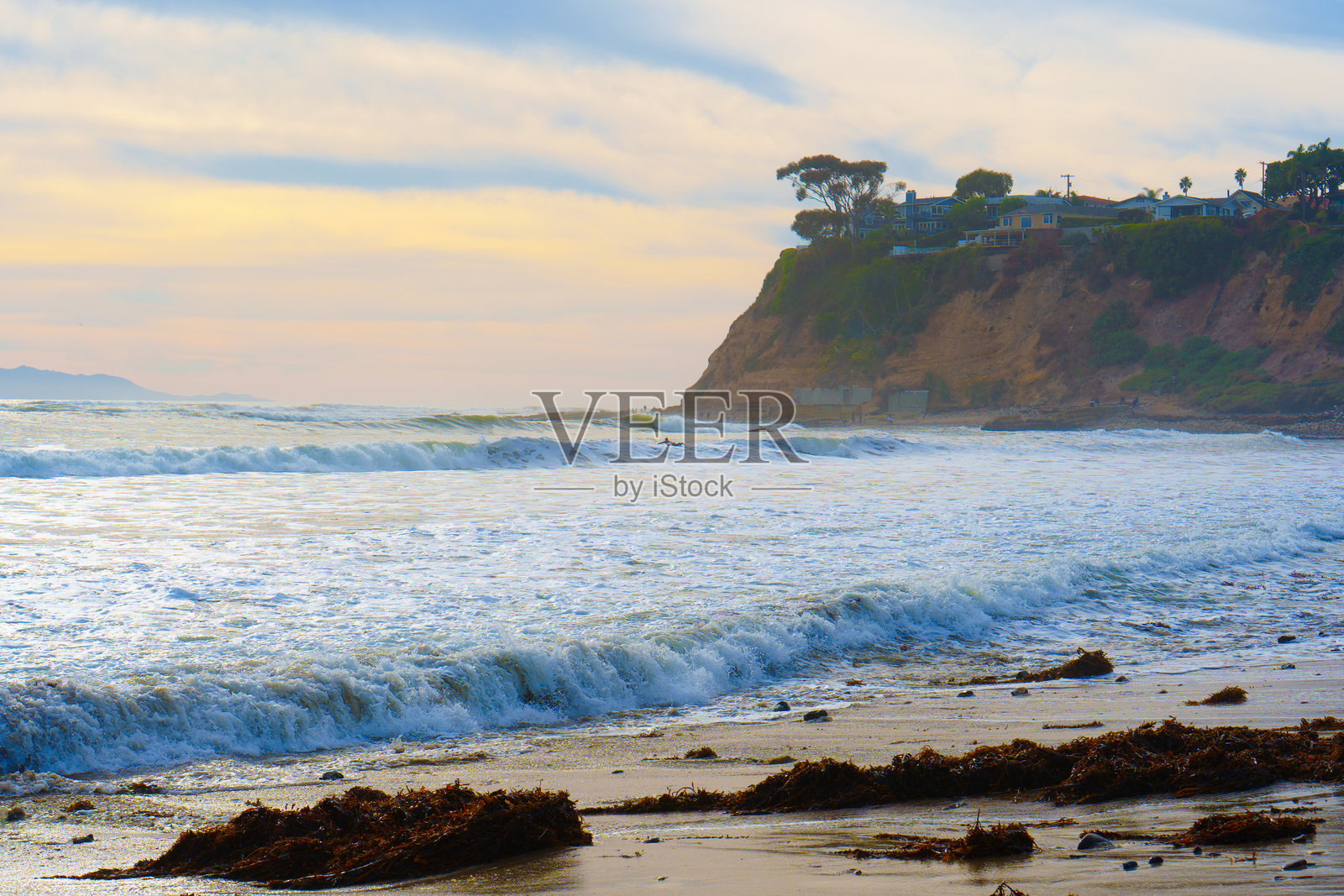 圣佩德罗海滩，冲浪者与海浪拍打悬崖边的房屋照片摄影图片